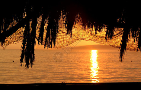 网编吊床以棕榈和渔网为形状的美好日落背景