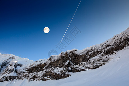 月亮轨迹Fr号山峰上空蓝天空的满月和飞机轨迹背景