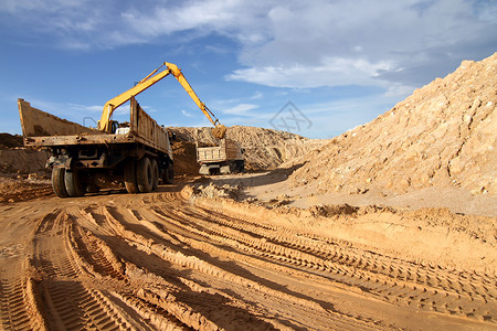 重型挖土机装载倾卸车卡车 在Bl上空采石场上装有沙子车辆倾倒推土机拖拉机土壤机器地面土地整车植物背景图片
