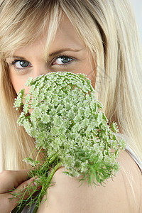 有个金发美女在脸前 拿着一朵绿花背景图片