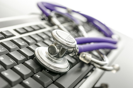 计算机键盘上的医学听诊器背景图片