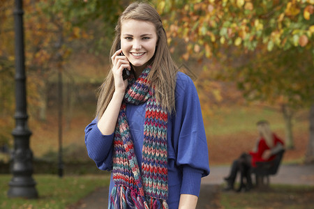 秋季公园带一对夫妇的秋边公园移动电话上的少女背景图片