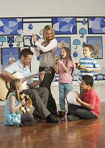 教师与有音乐课班级学生一起玩吉他团体教学音乐服装乐器老师瞳孔小学课堂休闲背景图片