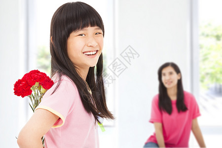 在母亲节给妈妈送康乃馨鲜花的小女孩女性孩子母亲展示女士孩子们礼物父母庆典花束背景图片