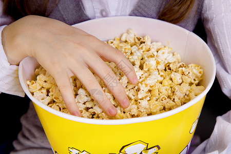 爆米花桶元素手放在一桶爆米花里手指孩子小吃黄色派对营养乐趣食物玉米白色背景