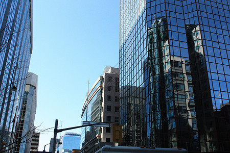 建筑物 旗帜和晴朗的天空反射在一座大楼的蓝色玻璃上 圣太后背景