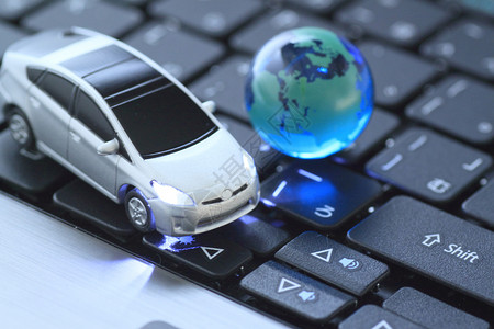 汽车里程玻璃球和玩具车在键盘上方里程全球行星互联网杂交种轿车世界旅行电脑地球背景