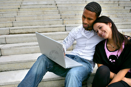 詹妮弗安妮斯顿一对夫妇用笔记本电脑坐在一些台阶上背景