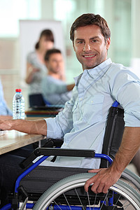 坐在轮椅上的男人男性桌子白色瓶子棕色头发微笑办公室工作背景图片