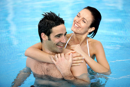 游泳的好处在游泳池拥抱的情侣乐趣微笑海水卫生护理夫妻假期男人福利漩涡背景