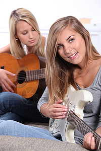 女孩弹吉他音乐娱乐声学金发女郎女孩们空闲排练友谊吉他微笑背景图片