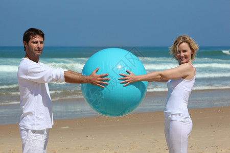 海滩游戏蓝球户外运动练习闲暇天空女士波浪体操娱乐灵活性背景图片
