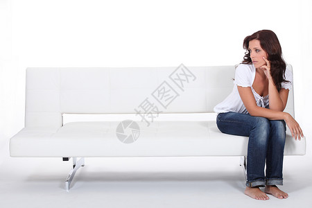 美丽的女人坐在沙发上寂寞朋友孤独服装师长椅赤脚时装房间女性设计师背景