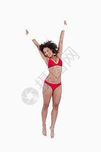 微笑的女人在她头上举着一张空白海报时跳跃背景图片