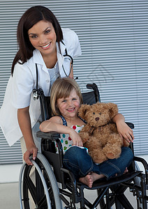 抱着女孩猪小女孩坐在轮椅上 抱着她的泰迪熊背景