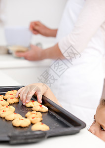 可爱的小女孩在妈妈做饭时吃饼干背景图片