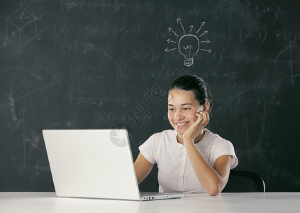 拥有膝上型电脑的青年学生桌子学校学习灯泡微笑女性笔记本乐趣青少年女孩背景图片