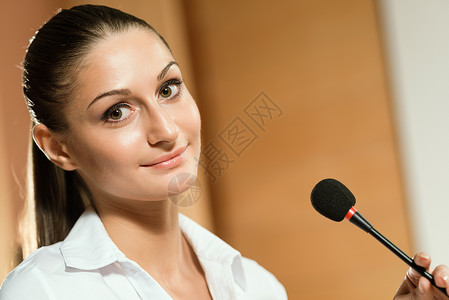 一名有麦克风的女商务人士的肖像会议主持人女士女性研讨会女孩商务办公室人士推介会背景图片