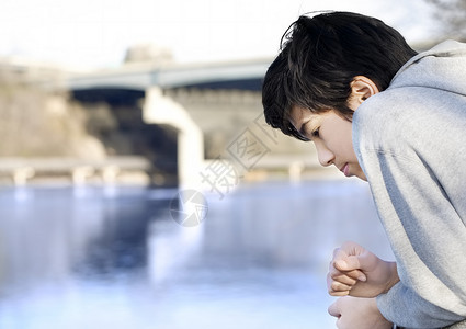 悲哀的少年男孩看着河边 想着高清图片