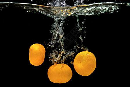 进店有优惠新鲜的橘子掉入水中 黑漆上有泡泡热带涟漪饮食海浪果汁橙子生活运动食物液体背景