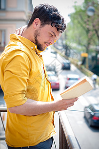 青年男子阅读书文化教育阳台衬衫年轻人黄色学生学习城市阅读背景图片