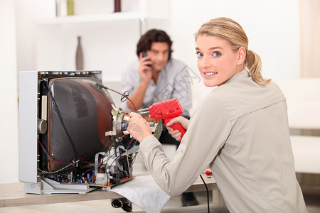妇女用焊烫铁修理电视机高清图片