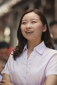 喜悦的年轻女性在北京街上露宿街头的肖像前景纽扣复合粉色愿望嘴巴幸福衬衫双臂棕色背景图片