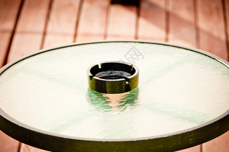 黑色空烟灰缸站在圆形玻璃桌的中间背景图片