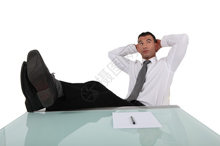 青年商务人士在桌子上和头后面用双腿断腿休息背景图片
