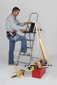 木匠用笔记本电脑站在梯子上石头修理工男性安全工匠工作室装修电气建筑劳动背景图片