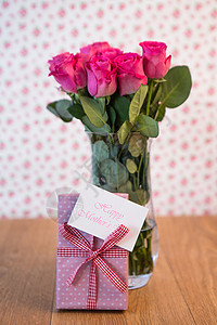 花瓶里的粉红玫瑰和粉红色的礼物 紧靠着它 母亲日卡背景图片