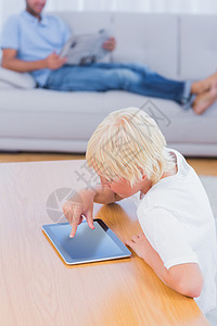 男孩在客厅用餐桌上的平板电脑背景图片