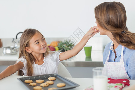 玻璃烤盘年轻女孩给妈妈一个曲奇饼背景