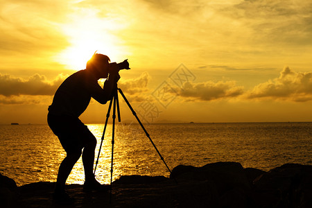 当你指向相机时日落时休光摄影师纸牌金子单人照片海洋石头岩石男性海岸三脚架背景