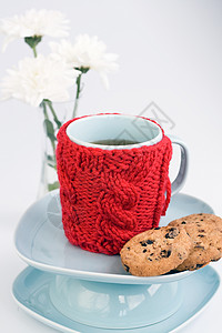 罩杯蓝杯 有红编织的罩子和巧克力饼干房子一杯茶厨房装饰假期杯子风格毛衣阅读针织品背景
