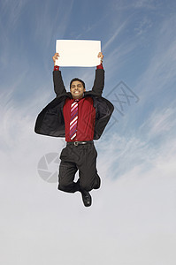 40岁出头欢快的商务人士在跳跃时拿着空白标牌背景