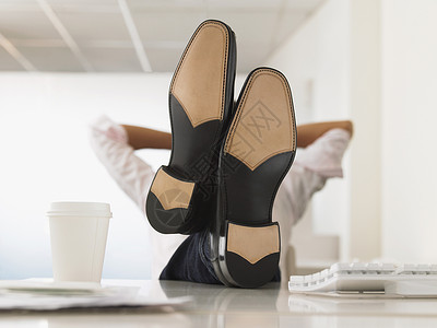 无鞋可及商务人士在办公室的电脑办公桌上站着脚坐直背景