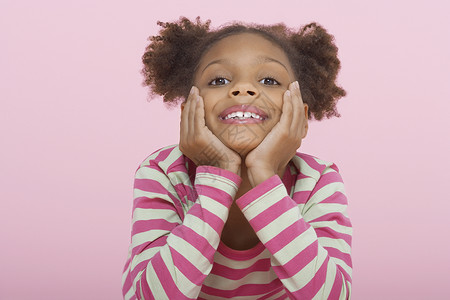 一个快乐的女孩的肖像 躺在下巴在粉红背景的手高清图片