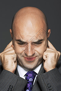 一名秃头商务人士在灰色背景下用手指耳朵闭着耳朵高清图片