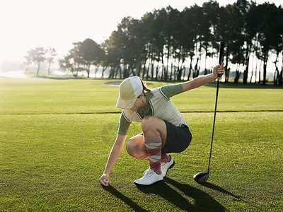 全年年轻女性高尔夫球手 将球投在踢球上高清图片