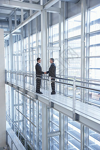 在现代办公室用扶栏手握手的商务人士成百上千背景图片