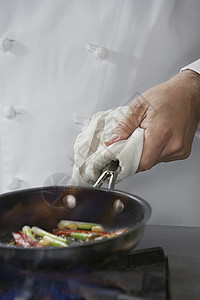 厨师在煎锅里烹饪食物的中间切口男性制服职业商业盘子蔬菜白色工作男人准备背景图片