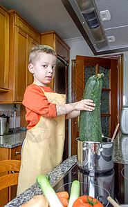 小厨房的桌子可爱的厨师 在锅里煮大菜乐趣童年饮食蔬菜洋葱食物男生烹饪韭葱微笑背景