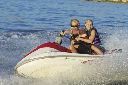 快乐的年轻夫妇在湖边骑水车飞溅高清图片素材