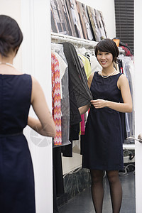 年轻女人站在镜子前的衣架边站着高清图片
