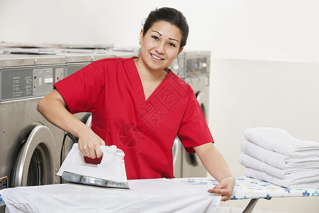 红板红色一名穿着洗衣房红制服熨衣的快乐女雇员的肖像;背景