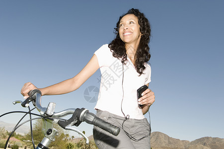 骑脚踏板中年成年妇女听MP3在山上骑着手柄的脚踏板背景