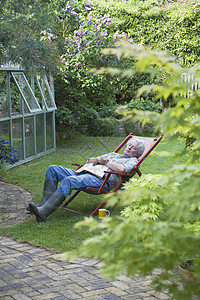 园丁睡在后花园的甲板椅子上高清图片