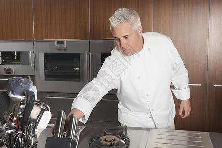 男厨员在商业性厨房里抢刀子背景图片