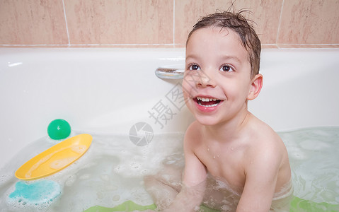泡澡的男孩泡澡时可爱男孩的幸福快乐孩子海绵乐趣洗发水婴儿喜悦浴室气泡泡沫肥皂背景